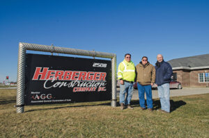 Two generations of Herberger mens tand by the Herberger Construction sign in Indianola, IA.